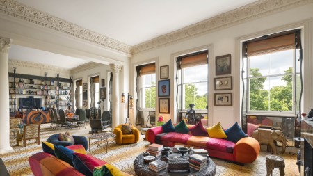 a room with large windows, sofas, and many paintings on the wall.