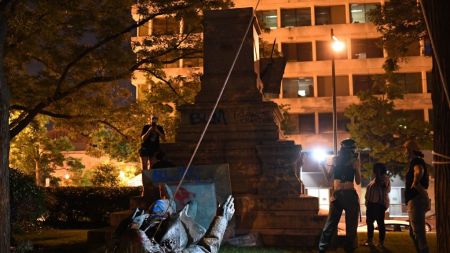 A group of people toppling a monument.