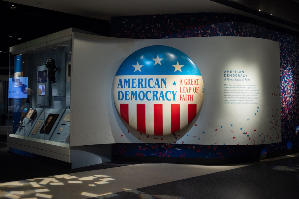 A museum display with a large button reading 'AMERICAN DEMOCRACY.'